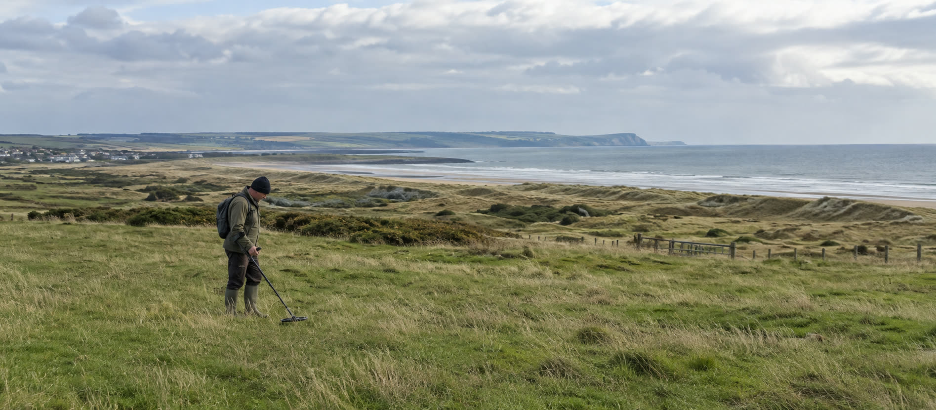 Detectorist surveying open British ground with a metal detector