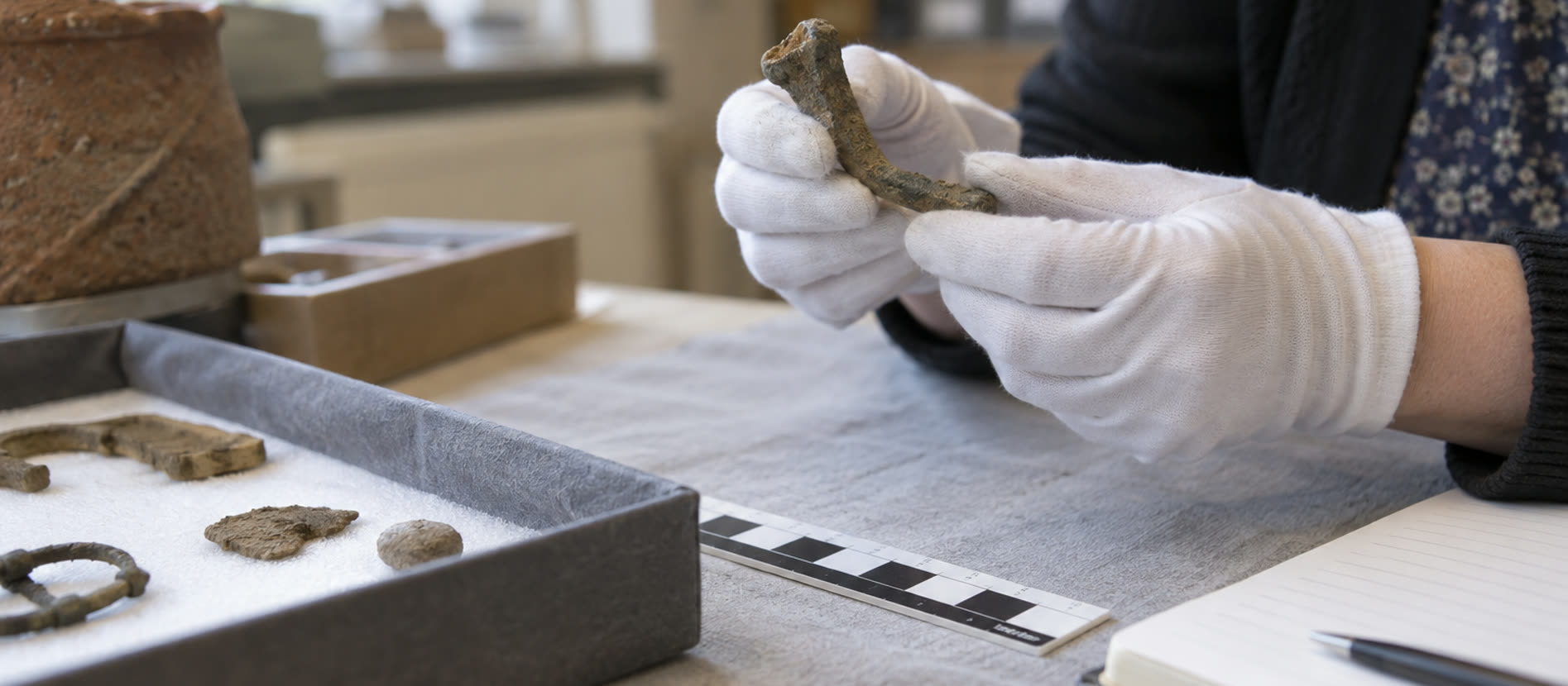 Specialist examining an ordinary archaeological fragment at a museum work table