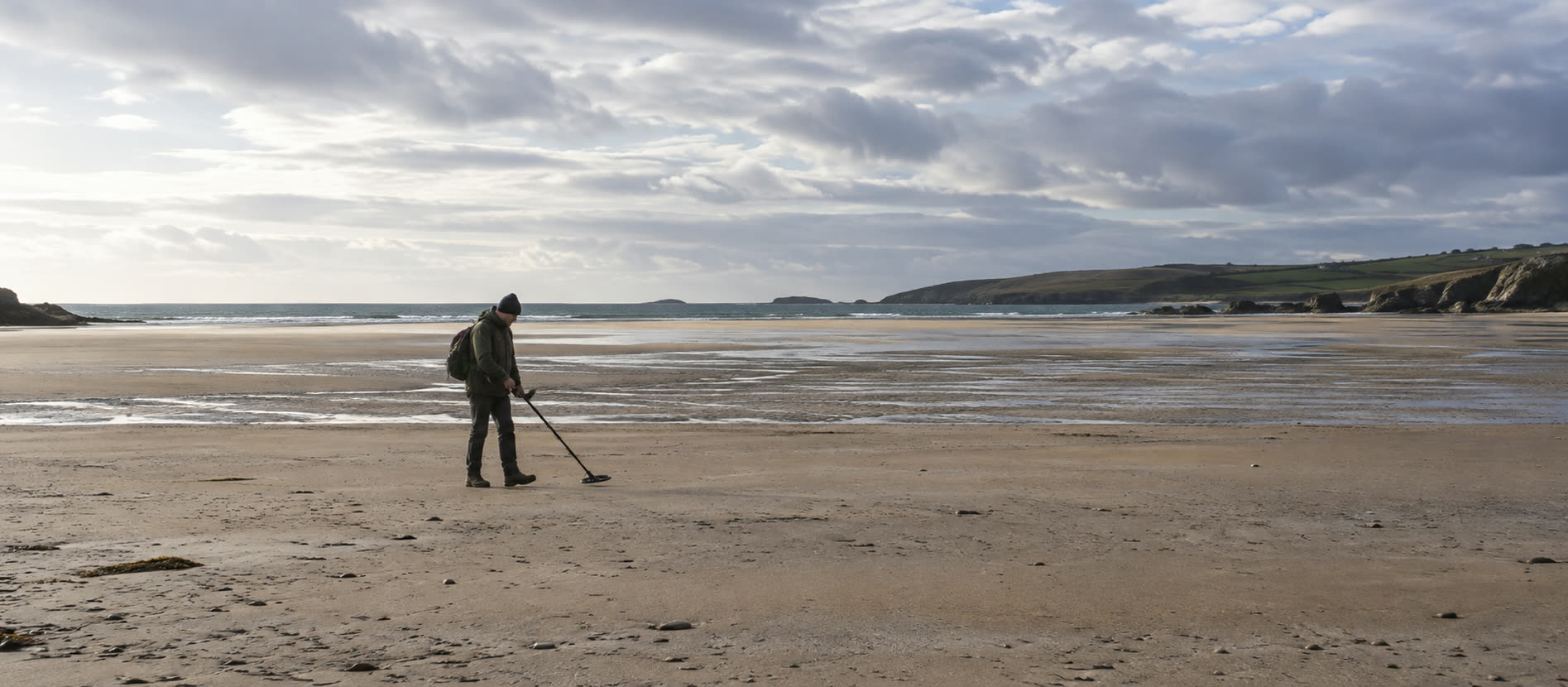 Detectorist on a wide British beach with a clear shore exit and distant waterline